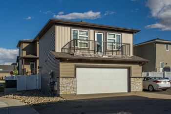 A house with a garage and a car parked in front.
